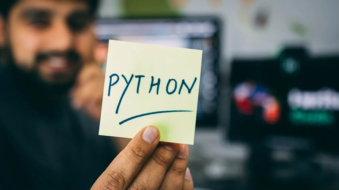 Image of someone holding a post-it note with the word Python